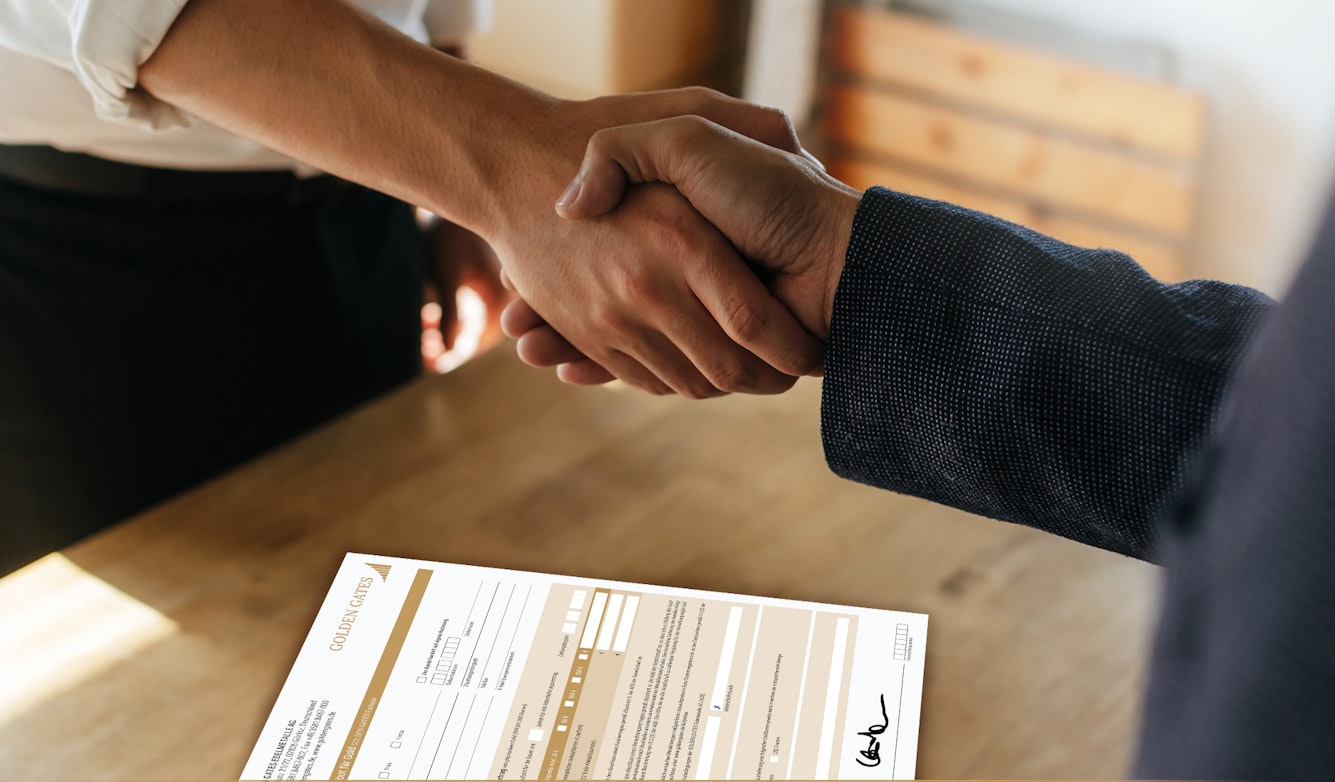 Zwei Personen, geben sich die Hand und besiegeln den Vertrag, welcher darunterliegt. Werden auch Sie Vertriebspartner der Golden Gates AG.